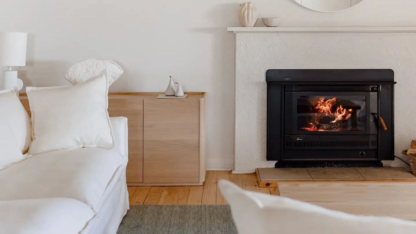 Hugo House, cozy living room with a fireplace, white sofa, and wooden cabinet.